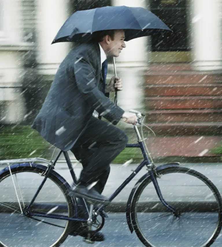 mężczyzna na rowerze trzymający parasol